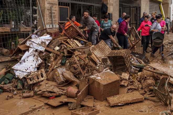 People clean mud from a shop affected by floods in Chiva, Spain, Friday, Nov. 1, 2024. (AP Photo/Manu Fernandez)