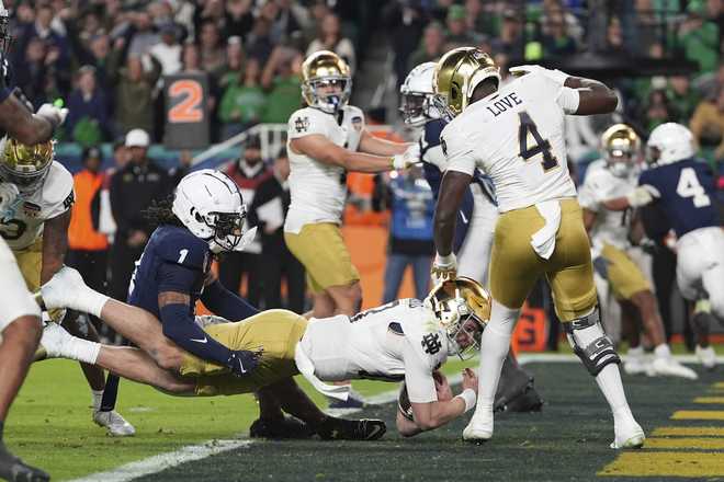 Penn State safety Jaylen Reed (1) attempts to hold Notre Dame quarterback Riley Leonard (13) as he scores a touchdown during the second half of the Orange Bowl NCAA College Football Playoff semifinal game, Thursday, Jan. 9, 2025, in Miami Gardens, Fla.